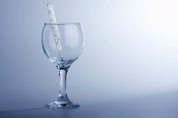 The thermometer in a glass on a blue background