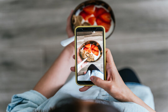 Hands of an unrecognizable person taking pictures of a healthy breakfast with a cell phone