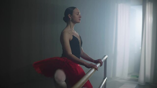 The art of choreography. A ballerina is training in a dance hall. A girl behind a ballet stand performs complex dance movements. High quality 4k footage