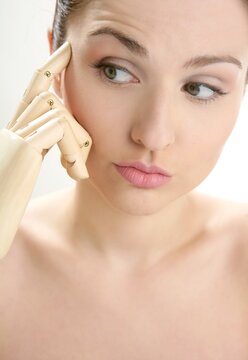Funny woman cosmetic portrait, thinking with mannequin wooden hand