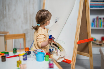 One toddler girl playing with painting tools and paint with colours, early child education and development, creativity concept 