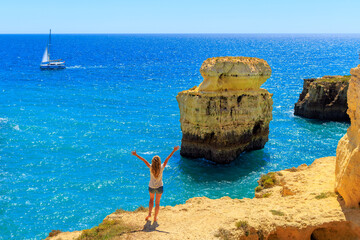 Happy woman enjoying beautiful view of atlantic ocean, rock formation and boat- vacation, summer...
