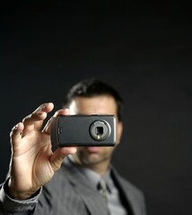 Businessman taking photos, mobile camera, black background