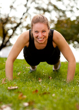A woman doing push-ups in the park