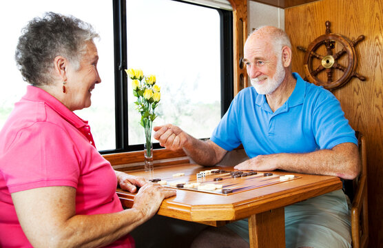 Senior couple playing backgammon in the kitchen of their motor home.