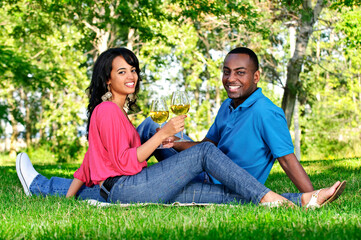 Young romantic couple celebrating with wine in summer park