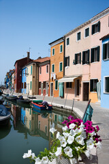 Fototapeta na wymiar Buildings and boats on a canal in Venice, Italy, with flowers in the foreground. Vertical shot.