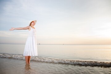 Fototapeta na wymiar Woman in hat and white dress on the beach