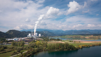 Smoking chimney at thermal power plant near lake and green nature. Aerial view