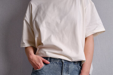 Woman in a white T-shirt poses near a white wall. Hand gestures and emotions. Studio photography....