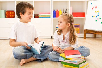 Fototapeta na wymiar Happy school boy showing her little sister how to read