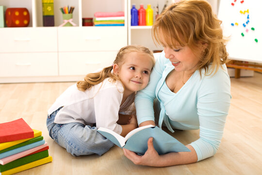Woman reading to her little girl, sitting on the floor