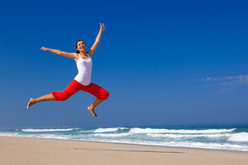 Beautiful young woman jumping on  the beach