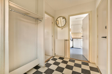 an empty room with a black and white checkered floor, mirror on the wall and door to the left