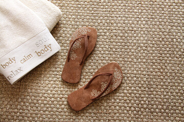 Flip flops with fluffy towels on seagrass rug