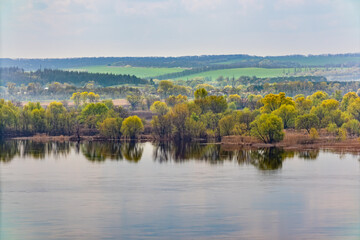 Spring landscape of the banks of the Dnieper river (Dnipro) from a height. Trees and fields, view of the horizon. View from above