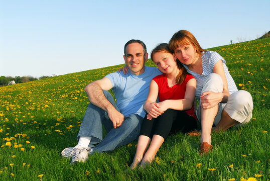 Portrait of a happy family of three on blooming summermedow