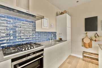 a kitchen with blue tiles on the backs and white cupboards, along with an oven in the middle part...