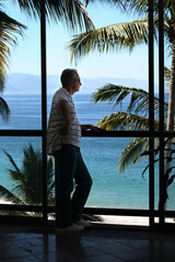 Man standing by the window in a tropical resort