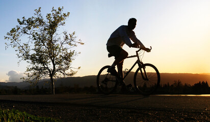 Fototapeta premium Man riding his bike at sunset