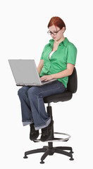 Redheaded teenager sitting on a high chair and working on a laptop.