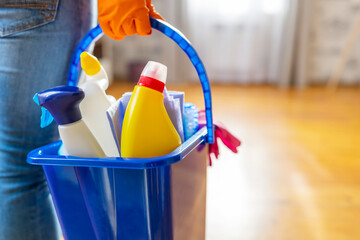 Woman in rubber gloves with bucket of cleaning supplies ready to clean up