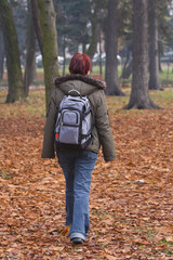 Redheaded backpacker girl walking in an autumn park.Shot with Canon 70-200mm f/2.8L IS USM