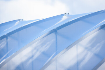 Transparent flexible roof of a greenhouse is under bright blue sky