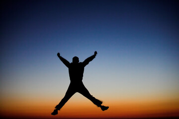 Fototapeta premium Silhouette of a man jumping against the sunset