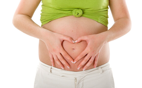 Pregnant woman showing her big tummy and making a Heart with the Hands