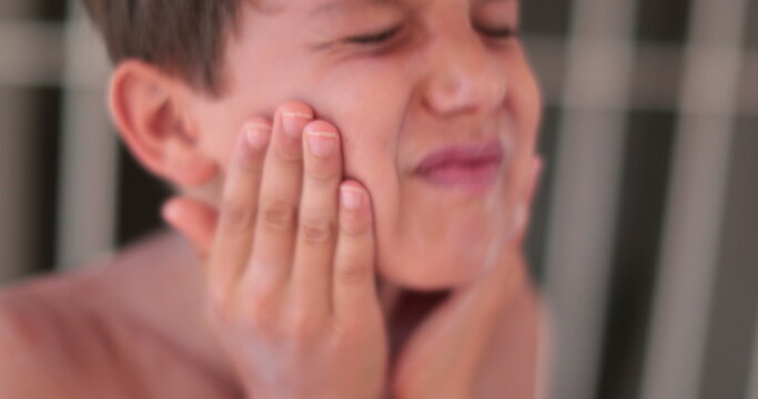 Child boy spreading sunscreen to his face. Kid applying sunblock lotion to himself