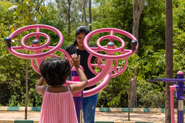 A Small Girl and Her Mom Play with Exercise Machine in Children's Park