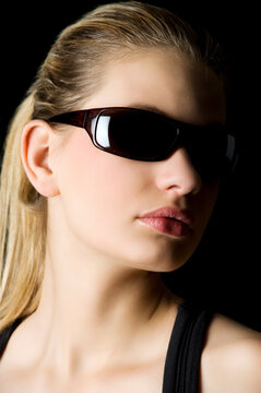 studio shot with strong contrast of a girl on black with dark sunglasses