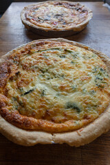 Quiche. Fresh eggs mixed with vegetables, bacon, ham, sausage, cheese, and Broccoli. The round shape on rustic wooden board.