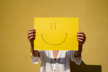 positive and smiley face emoticon on a yellow sign with copy space. Funny and Happiness Day. Yellow day