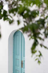 white house with blue door framed with leaves of a tree nisyros greece greek scenery minimalistic...