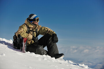 Fototapeta na wymiar snowboarder relaxing and posing at sunny day on winter season with blue sky in background