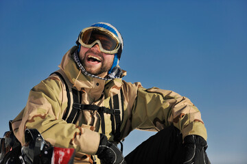 snowboarder relaxing and posing at sunny day on winter season with blue sky in background