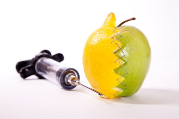 Lemon and apple stapled together and syringe.