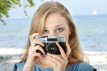 Pretty girl making photo using classic slr camera.