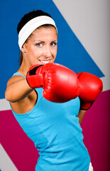 Attractive young woman with red boxing gloves in gym