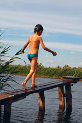 boy going along the river pier ready for diving