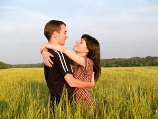 Teen couple embracing in field looking on each other