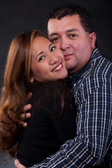 Portrait of an asian woman with hispanic man hugging over black