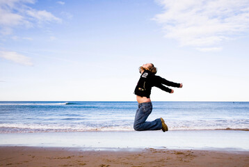 Fototapeta na wymiar Young Woman Jumping On A Beach