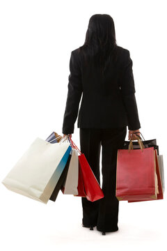 A Business Woman Is Carrying A Lot Of Shopping Bags, Shot From Back Against White Background.