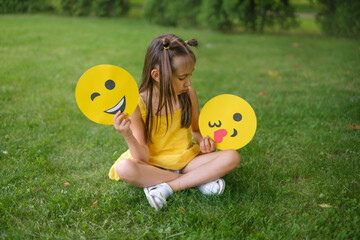 The girl makes a choice between a winking emoji and a smile face with a kiss