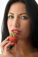 pretty brunette with a strawberry near her mouth with red lips