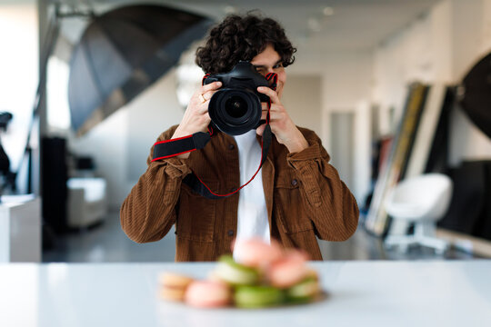 Male food and content photographer taking photos of delicious sweet macarons, working at photo studio
