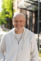 Portrait Of The Old Smiling Man Wearing Headphones Looking At The Camera. Sporty Positive Caucasian Man Wearing Headphones Looking At The Camera Before Running. Sport And Healthy Lifestyle Concept